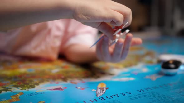 Closeup of Little Boy Playing with Small Toy Airplane on Big World Map
