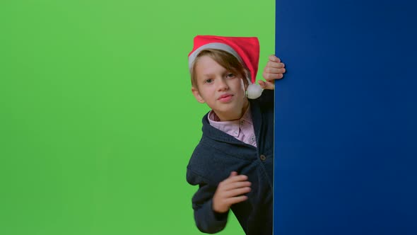 Child Boy Holding Hands on the Board Appears To Her in a Christmas Hat on a Green Screen