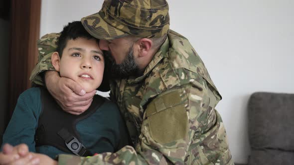 Military soldier kissing his son with disability at home