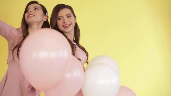 Pretty Twins in Pink Dresses Playing with Colorful Balloons