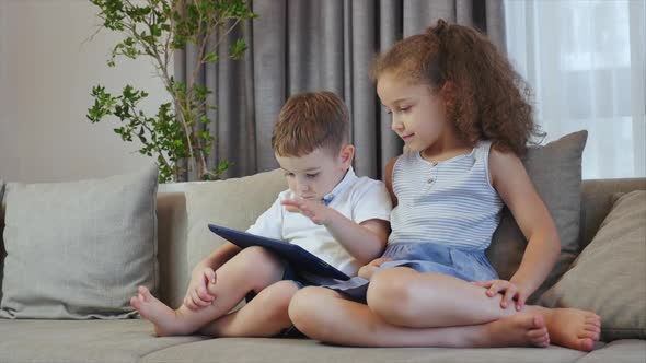 Cute Family and Daughter,sister-in-law a Nanny with Little Brother,looking at the Screen of a Tablet