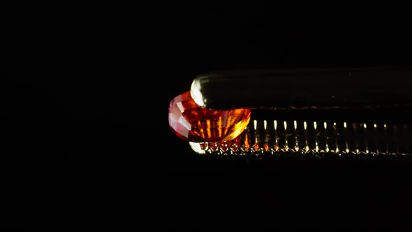 Natural Hessonite Brown Garnet Gemstone in the Tweezer on the Turn Table