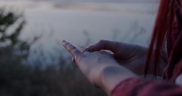 The girl anxiously holds on to the wedding ring on her finger against the background of sunset