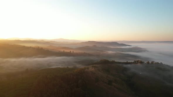 4K aerial view over a misty mountainous area. The great golden sun in the morning