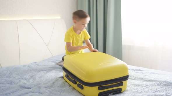 The Happy Boy Packed His Belongings in a Yellow Travel Suitcase. The Child Was Going on Vacation