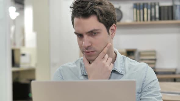 Pensive Creative Man Thinking and Working on Laptop