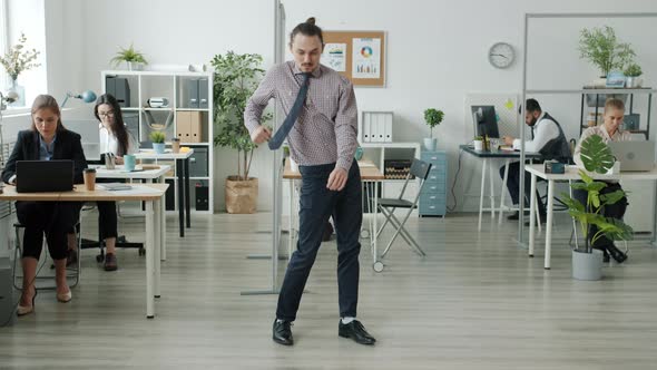 Portrait of Funny Man Dancing in Office While Businesspeople Working in Background