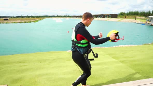 Man is dancing in the wake park. Throws helmet in the air and then catches it. Happy, joyful, smilin