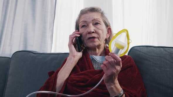 Vulnerable Old Woman Having a Phone Call and Using Inhaler