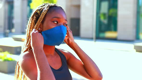 Sports Afro Woman Stands in a Mask on the Street in a Tracksuit and Wears a Medical Mask