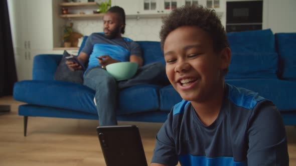 Happy School Age African Boy Browsing Funny Content Online on Cellphone Indoors