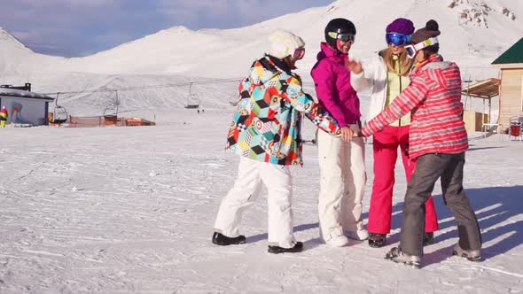 Teamwork of Four Caucasian Females Wearin Ski Costumes and Masks in Mountain Resort in Slowmotion