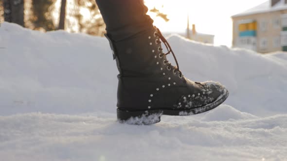 Female Feet in Black Boots Winter Walking in Snow