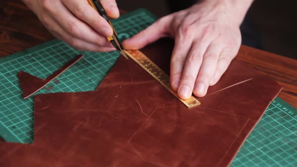 Man Tailor Cutting Artificial Leather with Ruler Closeup