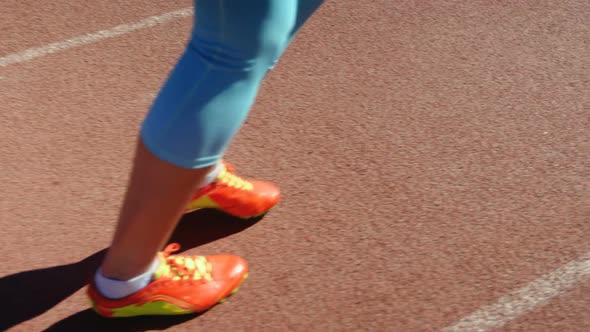 Low section of female athlete jogging on a running track 