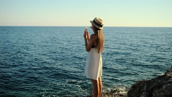 Woman is Taking Photo of Sea By Cellphone Standing on Shore