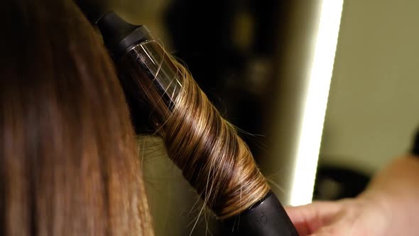 Hairdresser Makes Locks of Client Hair with Curling Iron