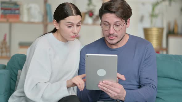 Hispanic Couple Using Tablet While Sitting on Sofa