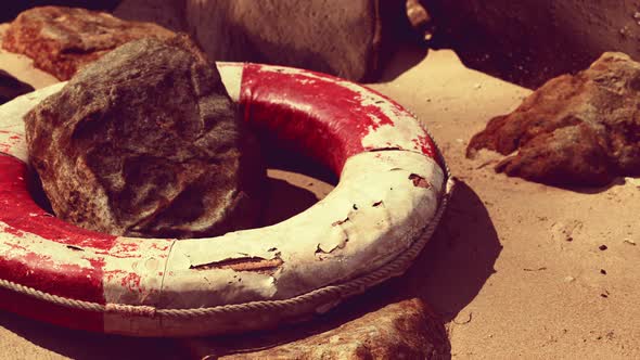 Old Damaged Lifebuoy on Sand