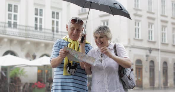 Happy Senior Tourists Stand Downtown and Enjoy the Rainy Weather in Lviv