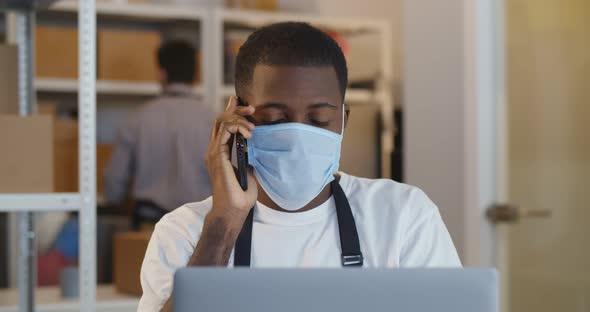 African Man Online Seller in Safety Mask Confirming Orders From Customer on Phone
