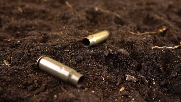 Bullet casings fall to the ground. Slow motion.