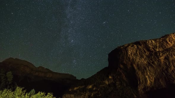Milky Way and Andromeda Galaxy move over nightsky with rock formation in foreground, Torla, Spain