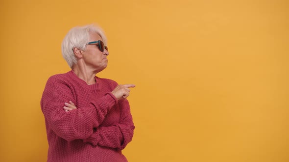 Trendy Bossy Granny with Sunglasses Pointing Finger on Empty Space and Nodding Her Head