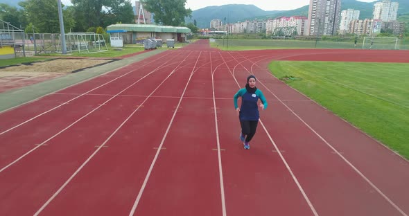 Cinematic Shot of Young Arab Sportswoman with Athletic Body in Hijab Running with Effort and