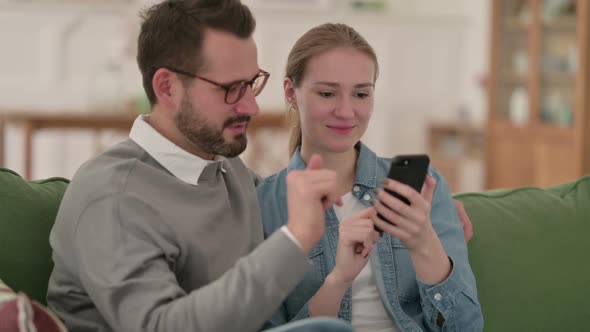 Happy Couple Using Smartphone Together at Home