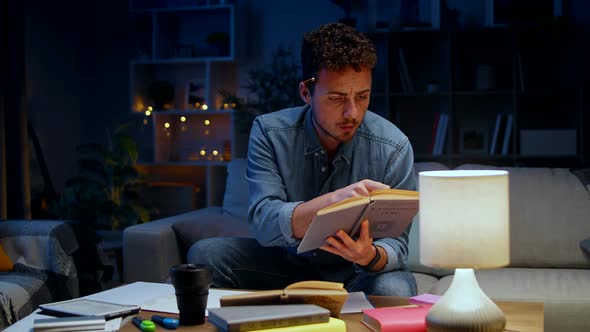 Young Man Makes Notes While Studying at Home in the Evening