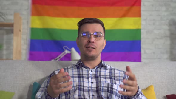 Man Blogger Middleaged in the Shirt on the Background of the Flag of the LGBT Records Video Close Up