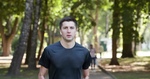 Man in Summer Sports Uniform Running in the City Park with Smartwatch for Measuring Speed 