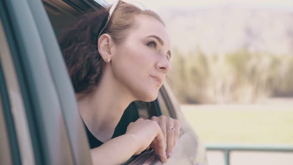 Girl with Long Lashes and Tattoo Leans Out of Automobile