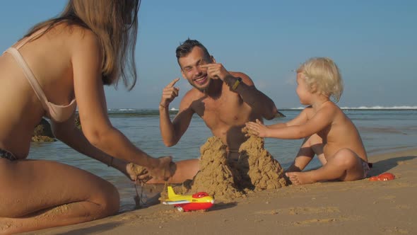 Parents Enjoy Leisure Time Making Hills From Sand on Beach