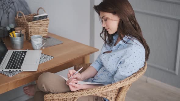 Young Woman Freelancer Works in a Cozy Home Studio