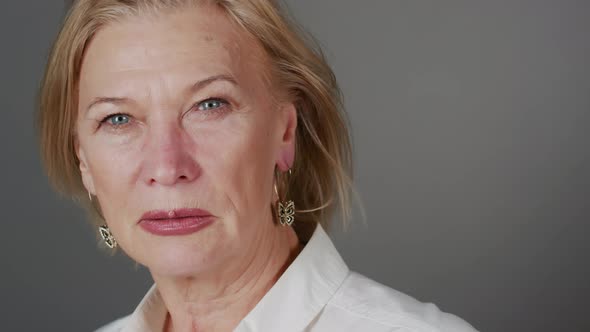 Close Up Portrait of Mature Blonde Woman on Grey Background