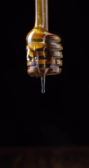Honey dripping from spoon in front of black background