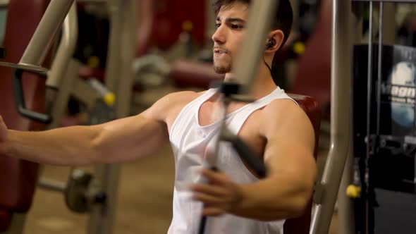 Extreme closeup of teen bodybuilder doing vertical chest press exercises on a machine at a fitness g