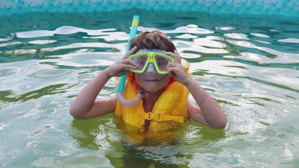 A Little Boy Putting on an Underwater Mask Standing in the Swimming Pool