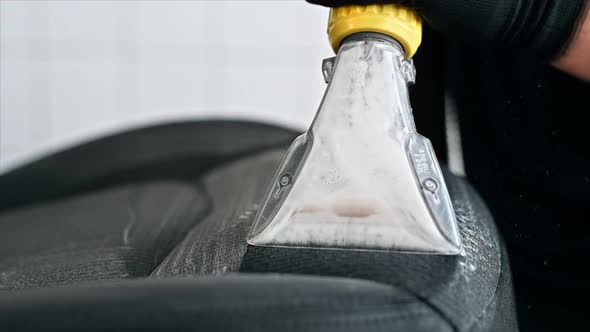 Working cleaner at car wash. Cleaning a seat using a professional vacuum cleaner. Slow motion