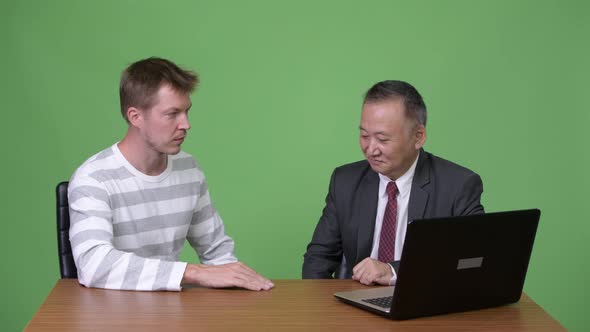 Mature Japanese Businessman and Young Scandinavian Businessman Working Together