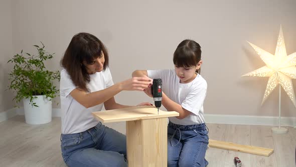 Happy Family Mother and Daughter Assembling Wooden Furniture Together with Screwdriver