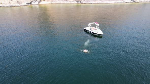 Young woman taking a bath in deep blue Okanagan Lake during a hot summer day in Canada. Aerial backw