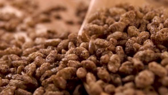 Chocolate flakes rice falls into a wooden spoon on a wood table