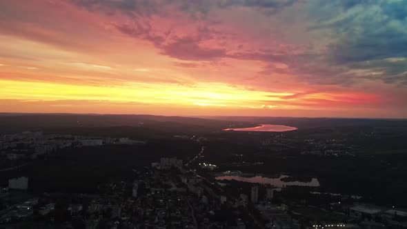 Aerial drone view of Chisinau, Moldova at sunset. Lakes, nightlights, roads with cars, buildings