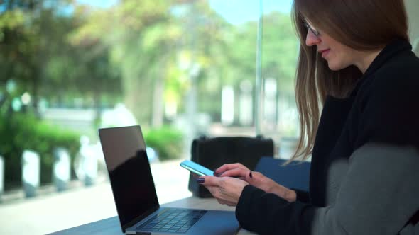 Serious woman writing in laptop during remote work