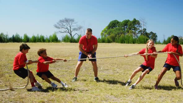 Trainer assisting kids in tug of war during obstacle course training