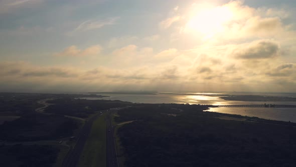 aerial pan right over the marsh & road facing the golden sunset at Jones Beach, New York