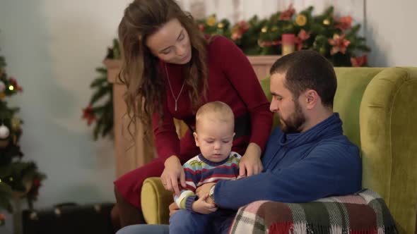 Mother, Father and Little Baby Are in the Room with Christmas Decoration